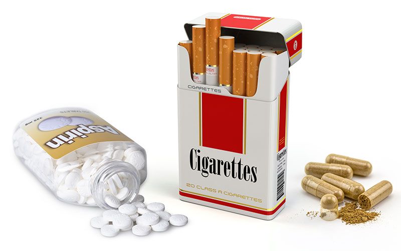 An aspirin bottle, a box of cigarettes, and an herbal supplement